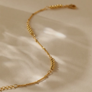 Detail eines 18K vergoldeten Perlenarmbands mit Karabinerverschluss und Verlängerung