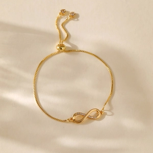 Detailed view of infinity charm with zircons on adjustable gold-plated box chain