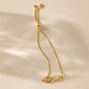 Close-up of gold-plated infinity bracelet with zircons and adjustable bolo sliding clasp