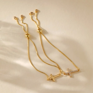 Detail of adjustable gold-plated cross charm bracelets with cubic zirconia and slide clasp