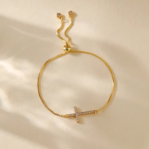 Macro detail of gold-plated cross bracelet with white zircon inlay and adjustable slide clasp