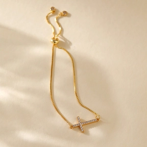 Macro shot of gold cross bracelet with shimmering stones and adjustable pull-string slider
