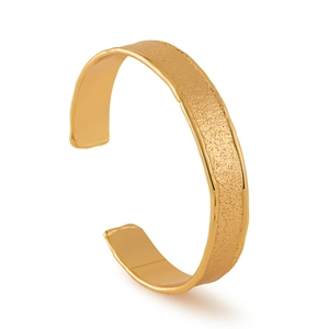 Detail eines breiten Armreifs mit goldener Textur und polierten Kanten im Design