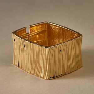 Detailed view of the textured gold square bangle featuring a tree bark pattern finish