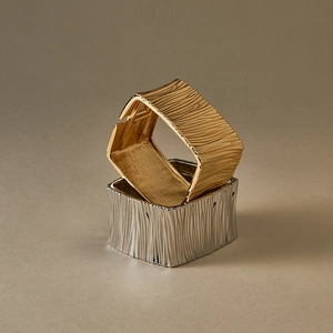 Detailed close-up of textured gold and silver wide bracelets with organic rock surface