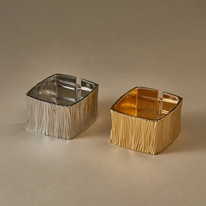 Detailed view of textured gold and silver wide cuffs with vertical wrinkled patterns