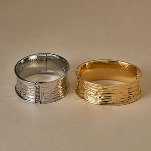 Detail of wide metal bangles with hammered water ripple texture and spring hinge