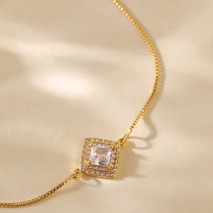Macro shot of gold plated box chain bracelet featuring a square zircon pendant with halo stones