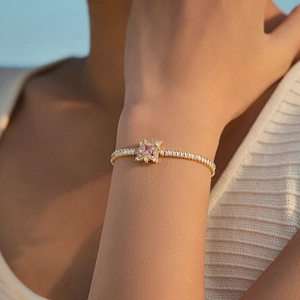 Luxury gold bracelet with pink flower center and square-cut zircon stones on wrist