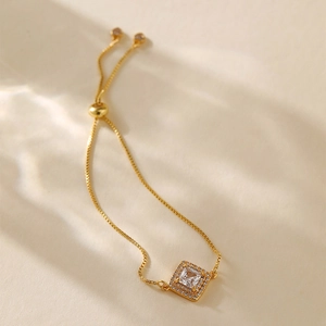 Detailed macro view of gold-plated slider bracelet with square halo cubic zirconia charm