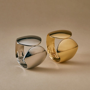 Macro shot of wide irregular gold and silver polished metal leaf cuffs with spring hinge