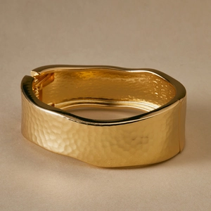 Detail of wide hammered gold bangle with irregular edges and spring hinge mechanism