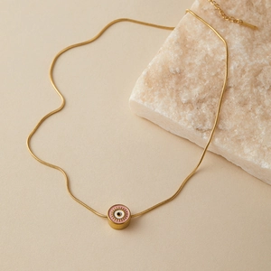 Dettaglio macro della collana a catena serpente dorata con pendente occhio in smalto rosa