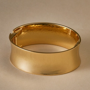 Detail view of wide gold hinged bangle with polished mirror finish and spring closure