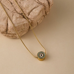 Dettaglio collana a catena serpente dorata con ciondolo occhio smaltato sulla roccia