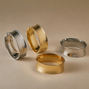 Macro detail of wide metal bangles in gold and silver with hammered and brushed textures