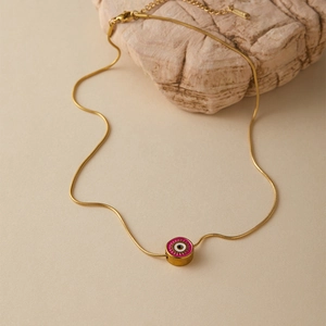 Dettaglio collana a serpente dorata con pendente occhio greco rosa su pietra naturale