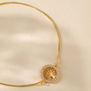 Close-up of gold-plated Tree of Life pendant with white cubic zirconia on a box chain