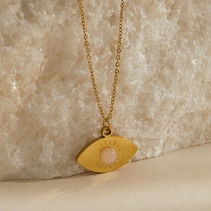 Dettaglio della collana occhio del diavolo dorata con quarzo rosa su pietra bianca