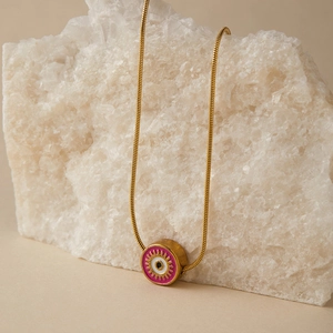 Dettaglio della collana occhio del diavolo dorata con ciondolo in smalto rosa su cristallo