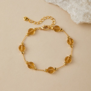 Detail of amber faceted beads on a fine gold chain bracelet with a lobster clasp