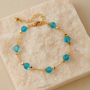 Detail of gold chain bracelet with sky blue faceted crystal beads and lobster clasp