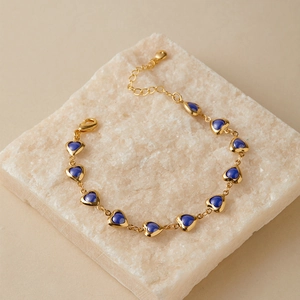 Detail of 18K gold plated bracelet featuring ten blue heart charms on textured stone