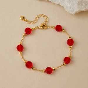 Detailed close-up of a gold-plated bracelet featuring faceted red crystal beads and lobster clasp