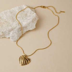 Dettaglio ravvicinato di una collana con ciondolo a cuore e strisce bianche e nere su piano