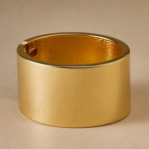 Detailed macro of golden metal cuff showing polished surface and inner wavy texture