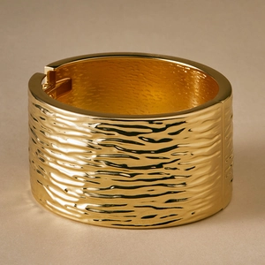 Detailed close-up of golden wide alloy cuff bracelet featuring a textured ripple surface