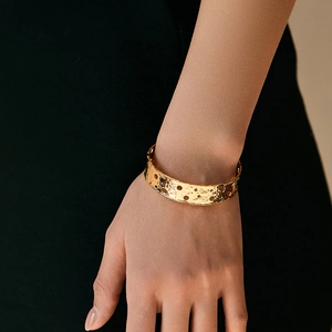 Unregelmäßiges vergoldetes breites Armband mit Aussparungen am weiblichen Handgelenk