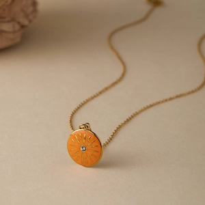 Dettaglio della collana malocchio con ciondolo a raggiera arancione e catena dorata