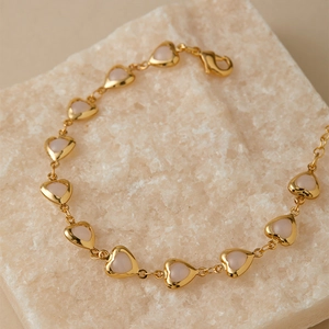 Detailed close-up of golden heart chain bracelet with pink crystal links and lobster clasp