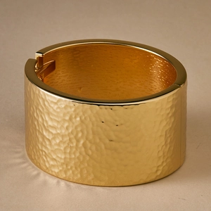 Detail of gold wide bangle with hammered texture surface and hinged closure design