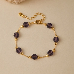 Macro view of purple faceted glass beads with gold spacers on minimalist chain bracelet