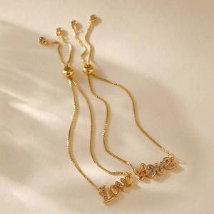 Detail of adjustable gold-plated bracelets featuring crystal Love charm and slide clasp