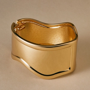 Macro shot of polished gold-finished irregular wavy hinged cuff bracelet with mirror texture