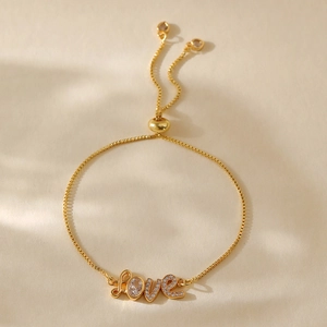 Close-up of gold plated Love heart charm bracelet with oval cubic zirconia and box chain