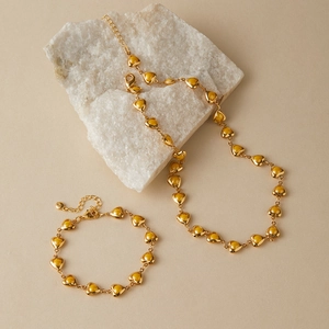Macro detail of gold-plated heart-shaped jewelry set with warm yellow enamel inlay