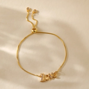 Detail of adjustable gold box-chain bracelet featuring a zircon-inlaid Love charm