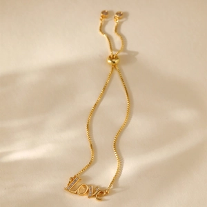 Detailed macro of gold plated Love charm bracelet with sparkling crystals and box chain