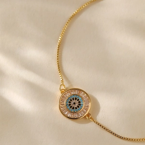 Macro detail of gold-plated evil eye bracelet with blue and white zircon inlay charms