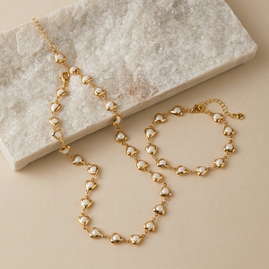 Detail view of heart-shaped links and gold-plated clasp on a vintage pearl necklace
