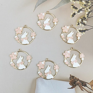 Macro shot of 6 bunny wreath pendants with pink bows and cherry blossoms for DIY jewelry