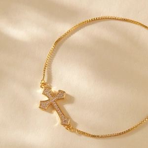 Close-up of gold-plated cross bracelet with zircons and adjustable box chain