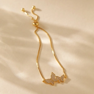 Detail of adjustable gold-plated slider bracelet featuring micro-pave butterfly charms