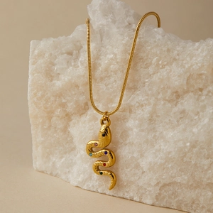 Collana con ciondolo a serpente dorato e gemme colorate su espositore minerale