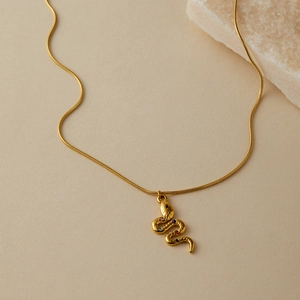 Dettaglio di una collana a serpente dorata con cristalli colorati e catena a serpente