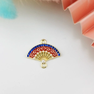 Macro detail of plum blossom fan jewelry connector with red enamel and blue rhinestones